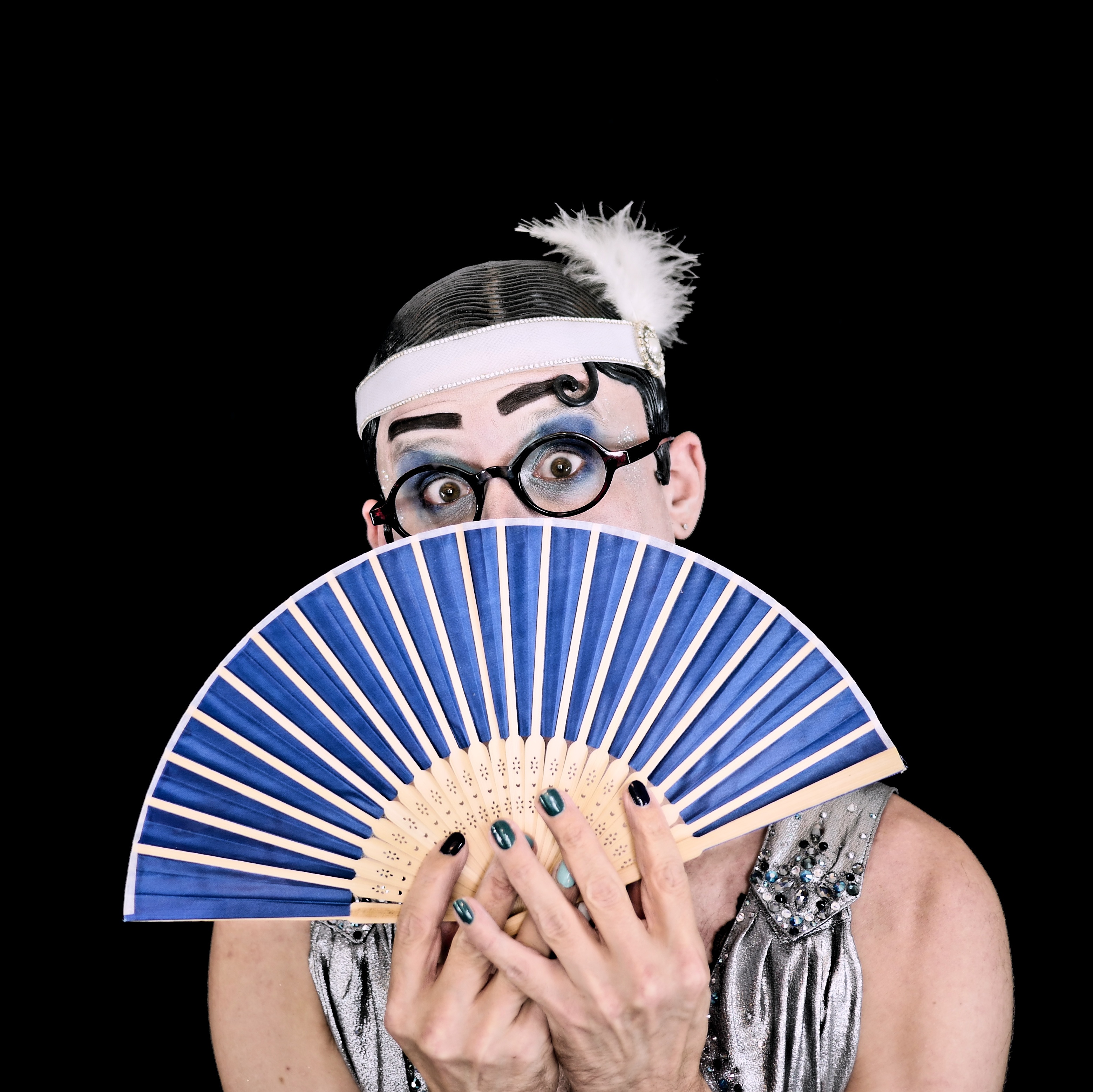 Enrico Touché stares from behind a blue fan